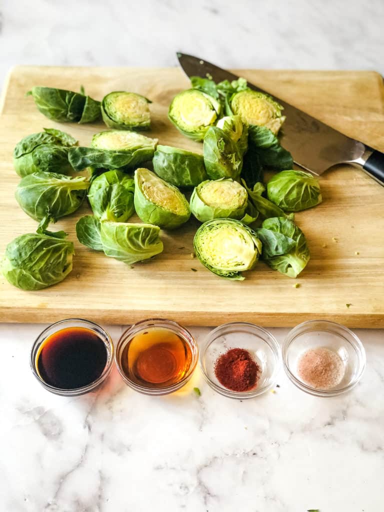 Ingredients for maple-glazed Brussels sprouts including cut sprouts, tamari, maple syrup, smoked paprika, and salt