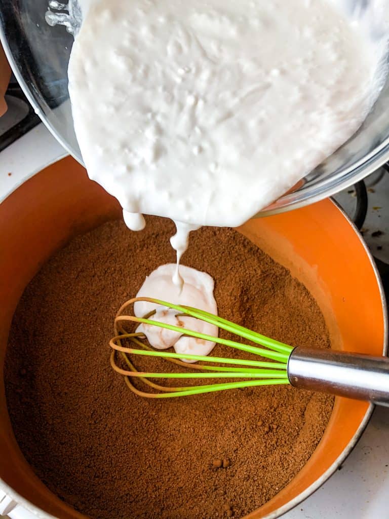 Pouring the coconut milk in the sugar and cocoa powder mixture.