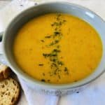 roasted butternut squash soup in bowl with sliced bread on the side