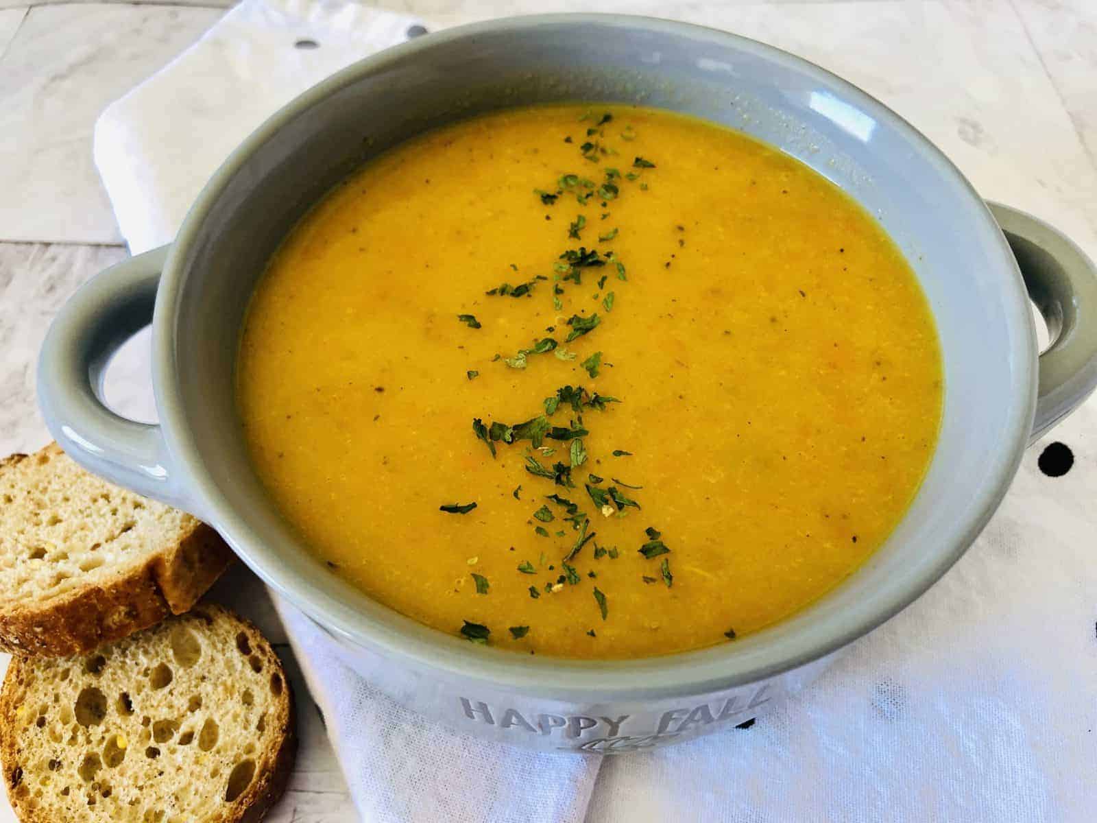 roasted butternut squash soup in bowl with sliced bread on the side