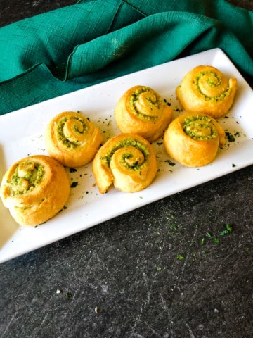 cooked pesto dinner rolls on a white tray