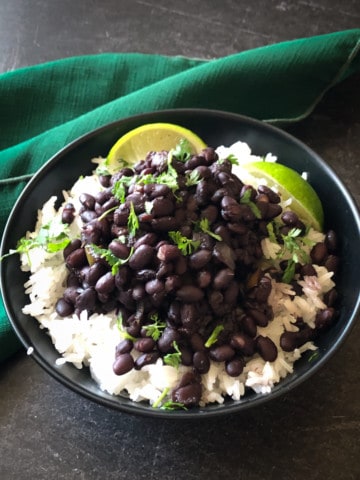 Cuban black beans over rice with limes on the side and cilantro on top