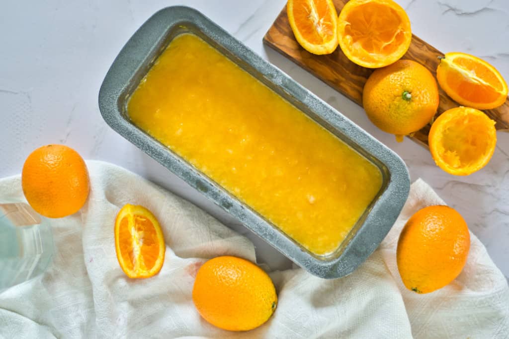 pan with orange sorbet in the process of freezing with orange pieces in the background