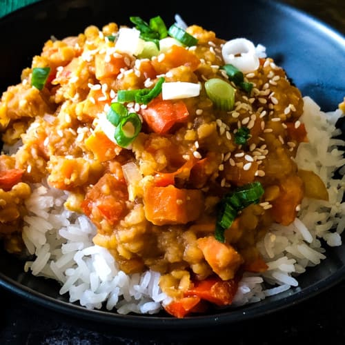 Red lentils on rice in a black bowl