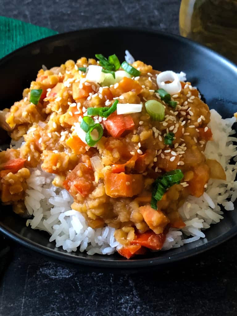 Red lentils on rice in a black bowl