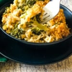 A fork serving up a delicious bite of Broccoli Rice Casserole in black bowl