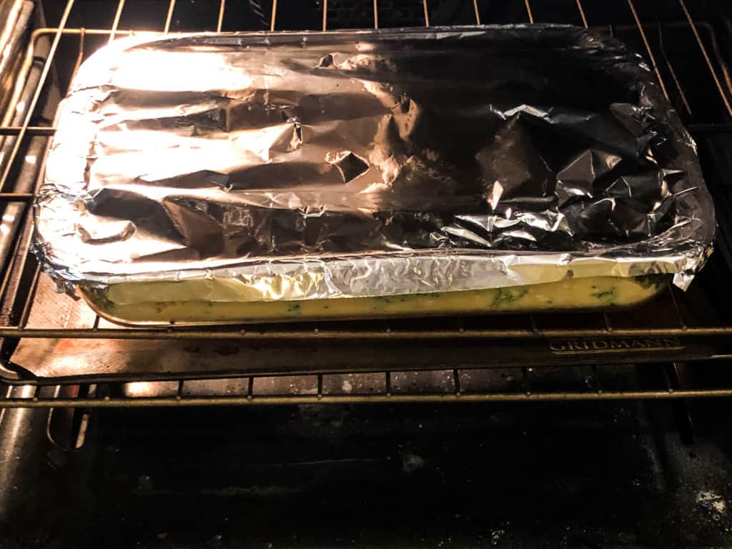 broccoli rice casserole covered with foil in the oven
