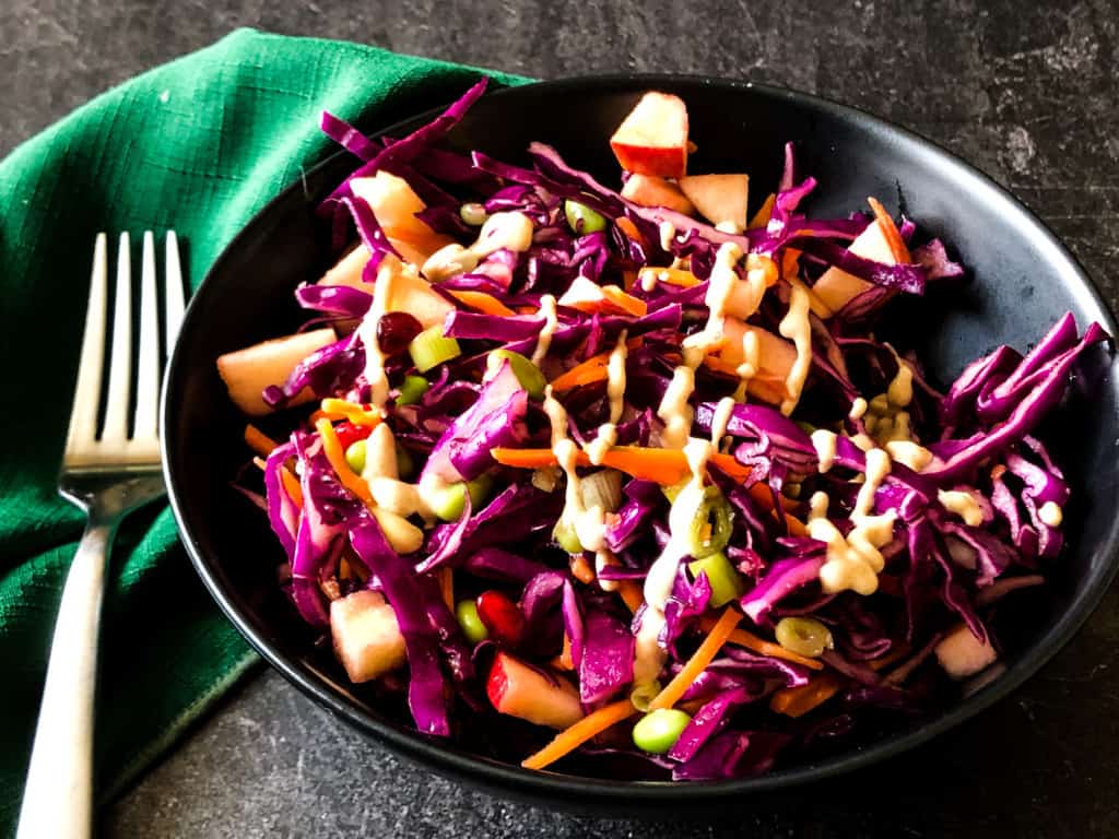 purple cabbage slaw in a black bowl with creamy miso sauce