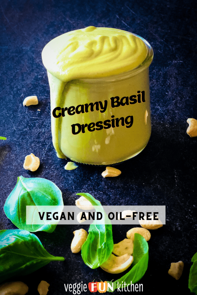 creamy basil dressing in a jar with cashews and basil leaves in the foreground with Pinterest text overlay