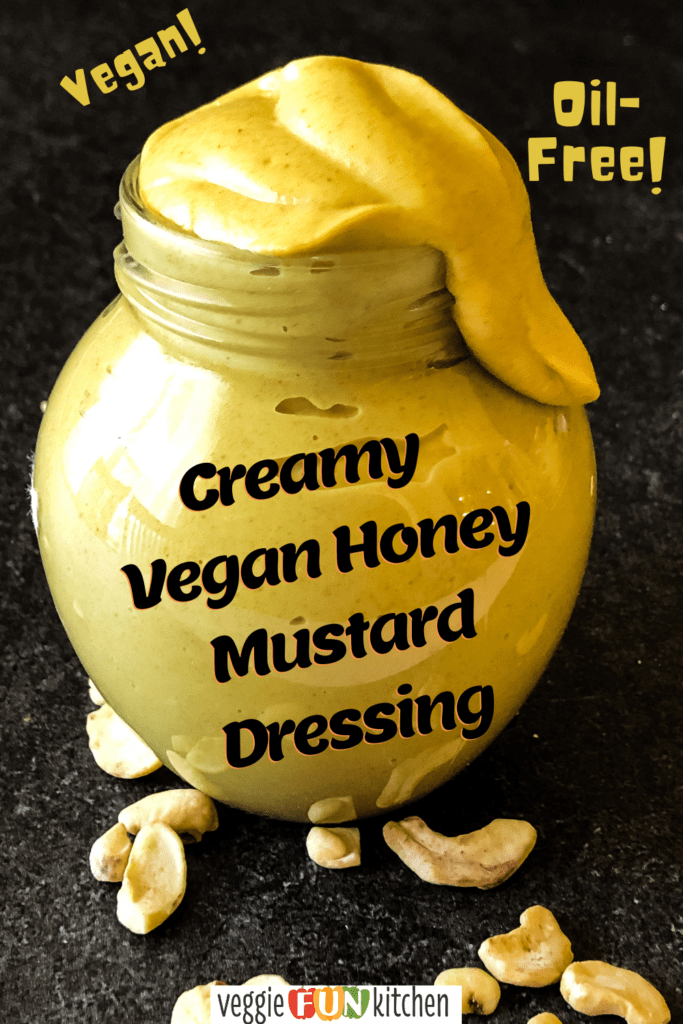 vegan honey mustard dressing in a small jar with an unsightly amount dribbling from the top with raw cashews in the foreground with Pinterest text overlay