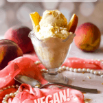Peaches and cream ice cream in a glass dish with peaches sticking out of the top. a scarf, pearls, and spoon in the foreground. Peaches in the background. With Pinterest text overlay