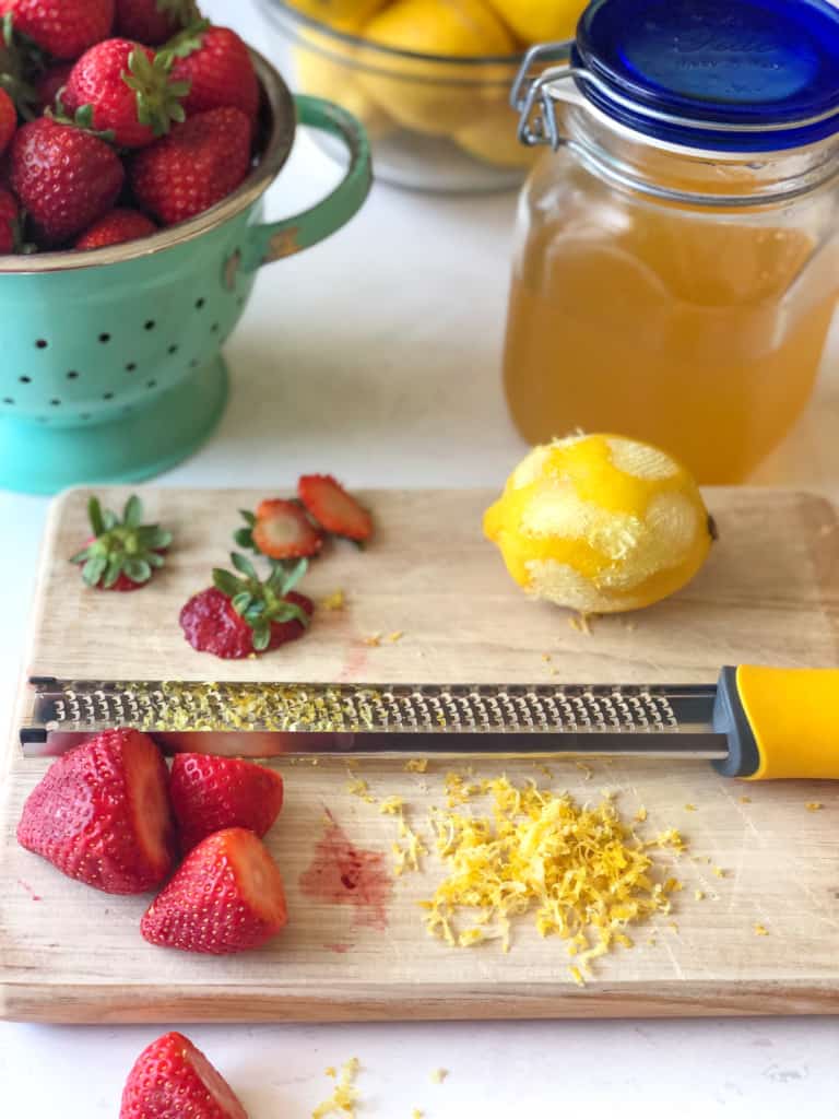 Ingredients needed for strawberry lemonade sorbet including fresh strawberries, lemonade concentrate and lemon zest