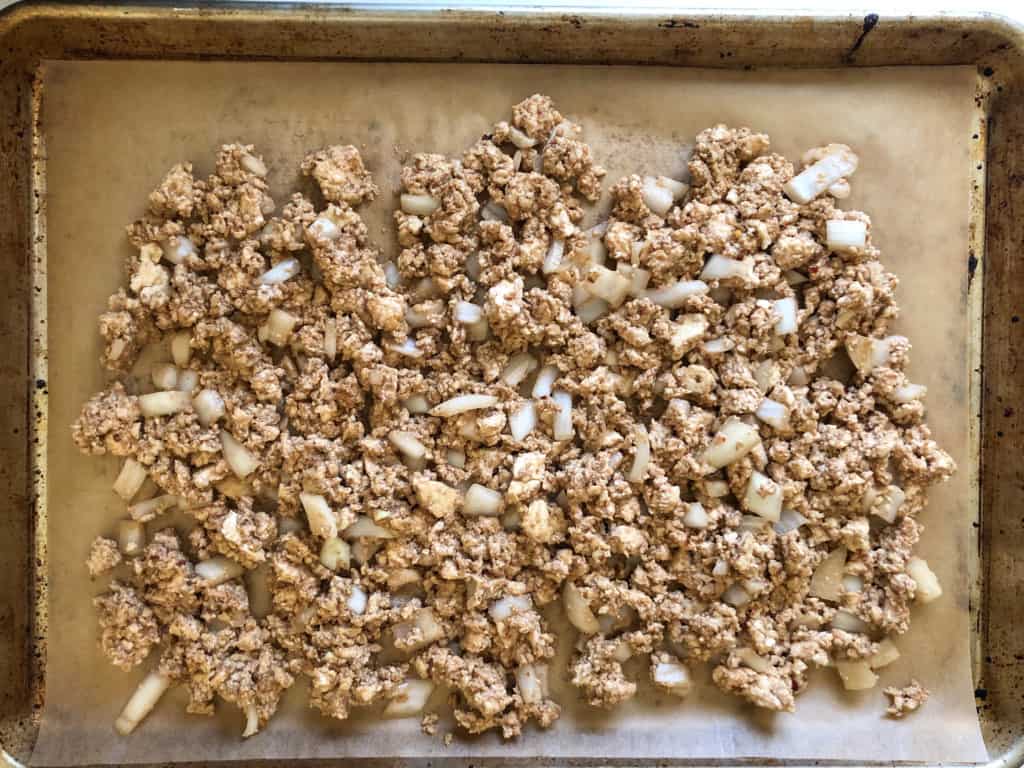 uncooked asian tofu crumbles on parchment lined baking sheet b