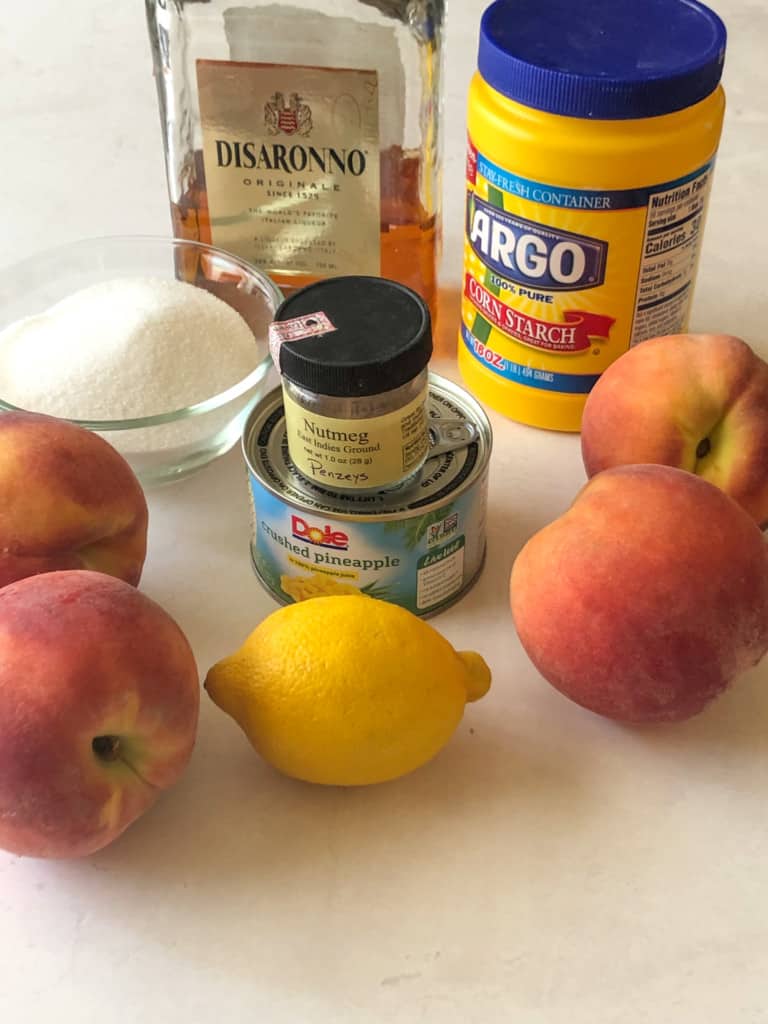 ingredients for peach butter including peaches, sugar, nutmeg, crushed pineapple, cornstarch, and amaretto
