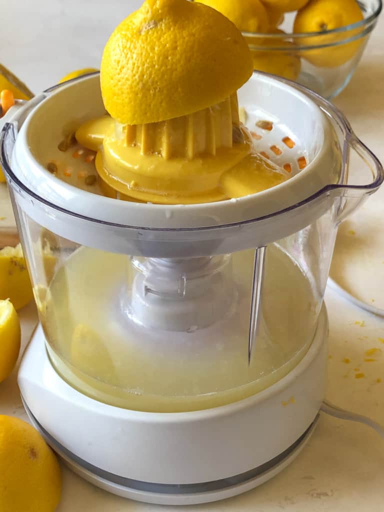 juicing a lemon half on a citrus juicer