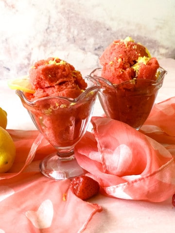 two ice cream dishes with strawberry sorbet topped with lemon zest
