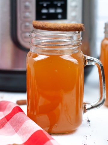 apple cider in glass mugs with apples and cinnamon sticks