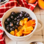 bowl of oatmeal topped with blueberries and peaches