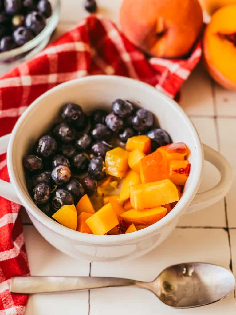 bowl of oatmeal topped with blueberries and peaches
