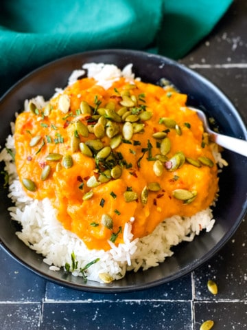 butternut squash sauce over rice topped with pumpkin seeds in black bowl