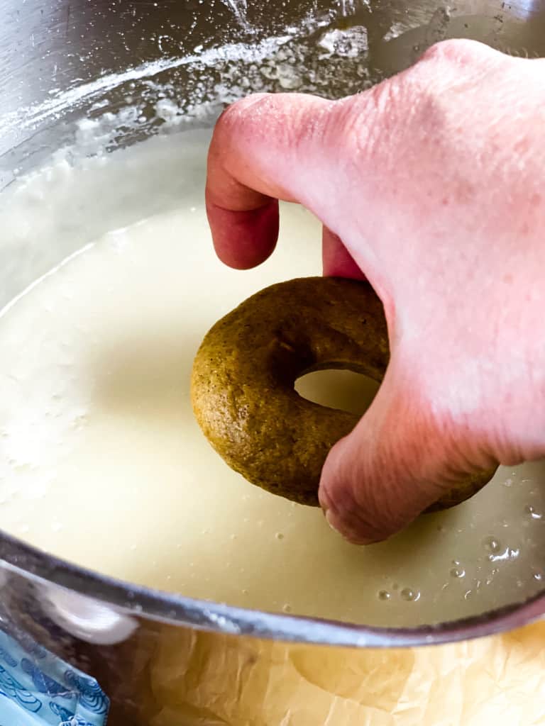hand dipping baked donut into glaze