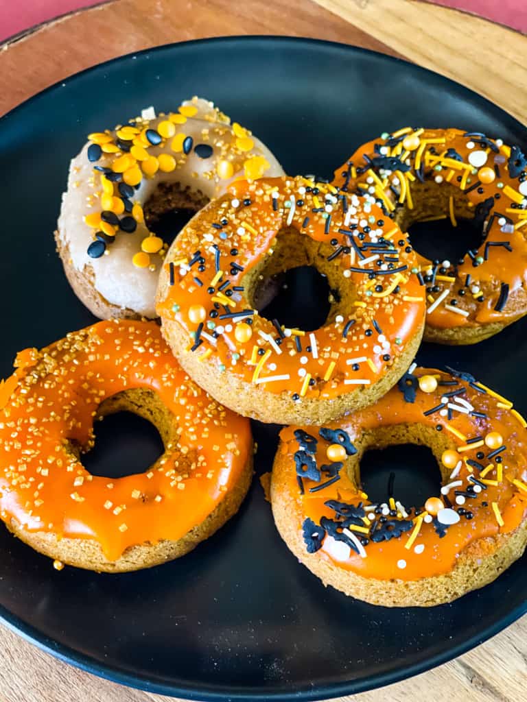 black plate with five halloween sprinkled baked donuts
