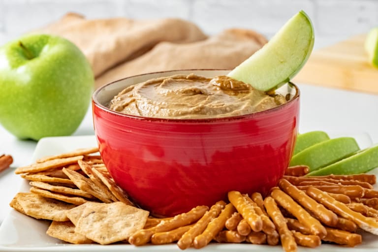 red bowl with gingerbread hummus with pretzels, crackers, and green apples