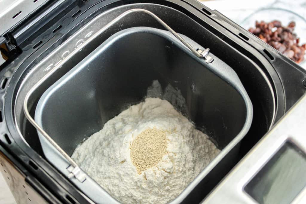 ingredients for cinnamon raisin bread in bread machine showing yeast on top of the bread flour