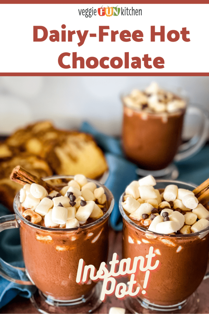 Three glass mugs of hot chocolate topped with marshmallows, mini chocolate chips, and cinnamon sticks. Slices of cake are in the background with pinterest text overlay