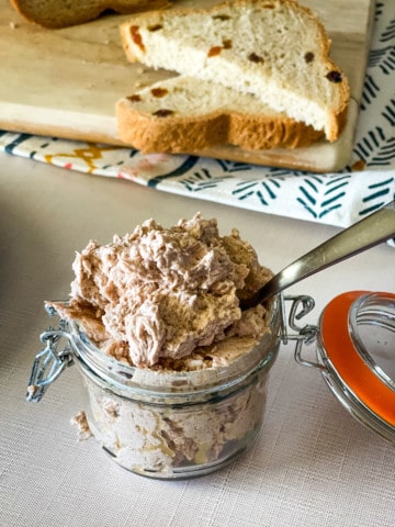 Maple Cinnamon butter in glass container with cinnamon raisin bread in the background