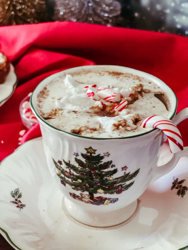Christmas tree cup with peppermint mocha inside, topped with coconut whipped cream, and candy canes