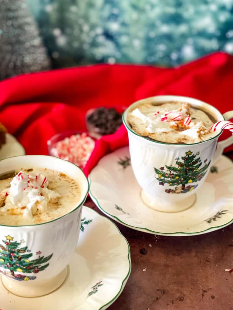 two Christmas tree cups with peppermint mocha inside, topped with coconut whipped cream, and candy canes