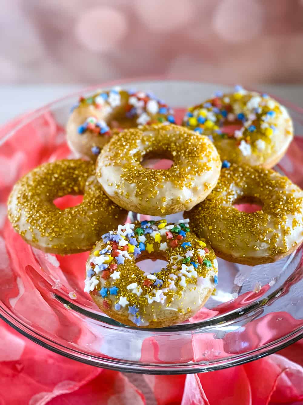 glass cake plate holding glazed decorated donuts