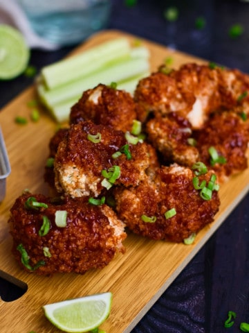 tray of cauliflower wings with limes in front, celery and dip