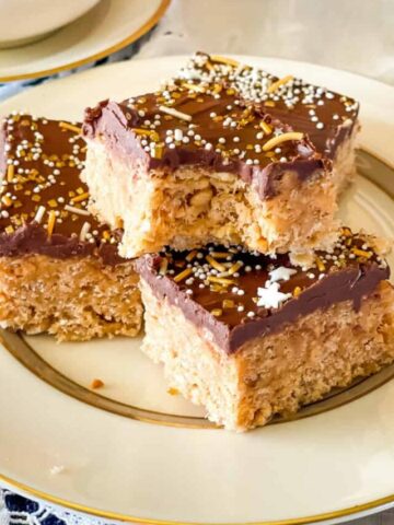 three rice krispy treats on a plate with lace napkin and filled coffee cup