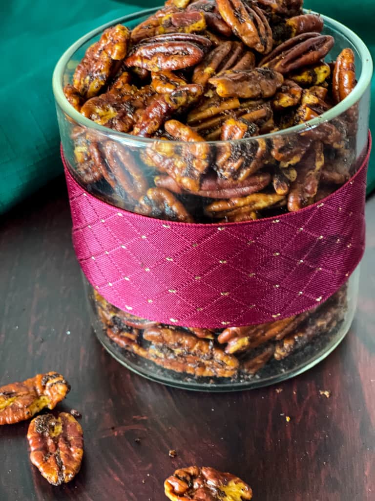 jar of savory pecans with fuchsia ribbon and scarf in background