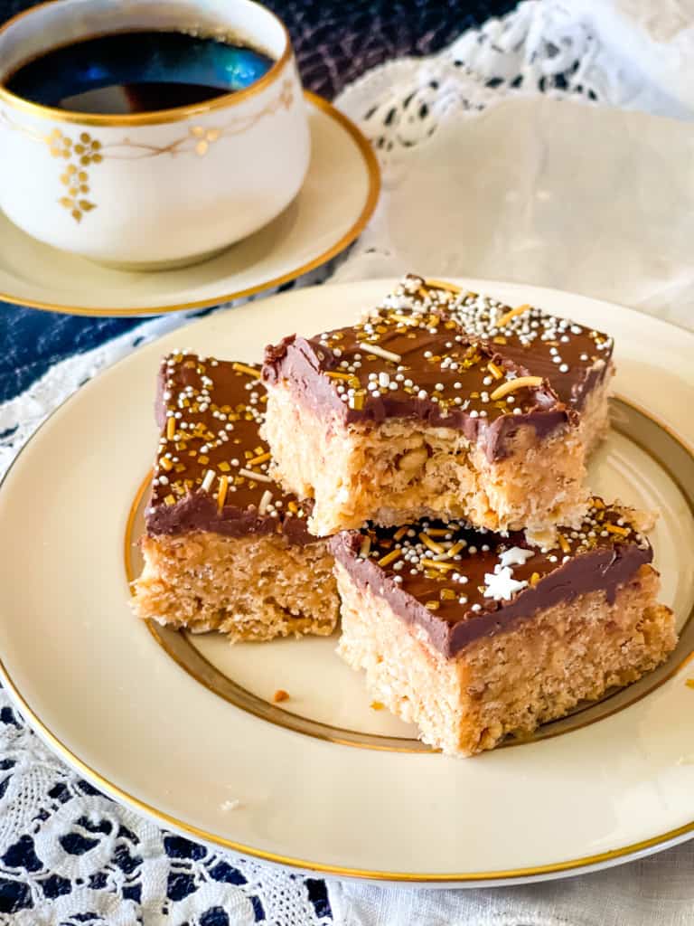 three rice krispy treats on a plate with lace napkin and filled coffee cup