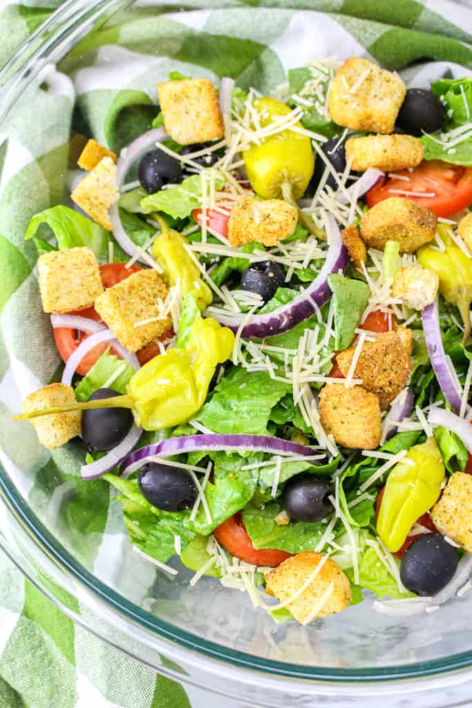 glass bowl with Italian salad tossed with dressing