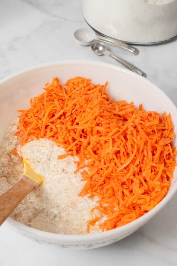 mixing shredded carrots in carrot cake