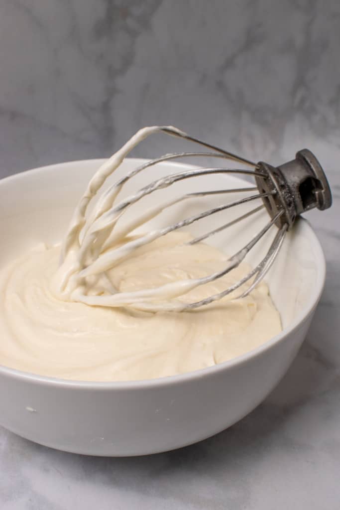 bowl of cream cheese frosting with whisk attachment in bowl