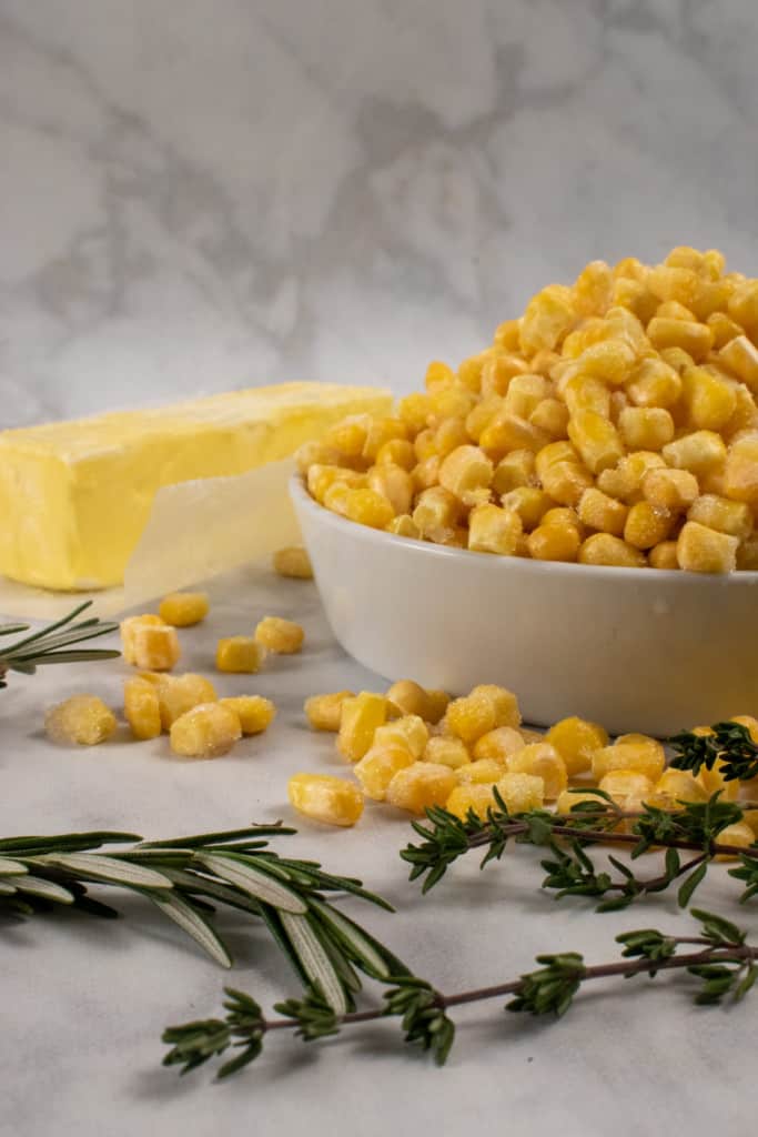 ingredients to make vegan buttered herb corn including vegan butter, corn kernels, fresh thyme, and fresh rosemary