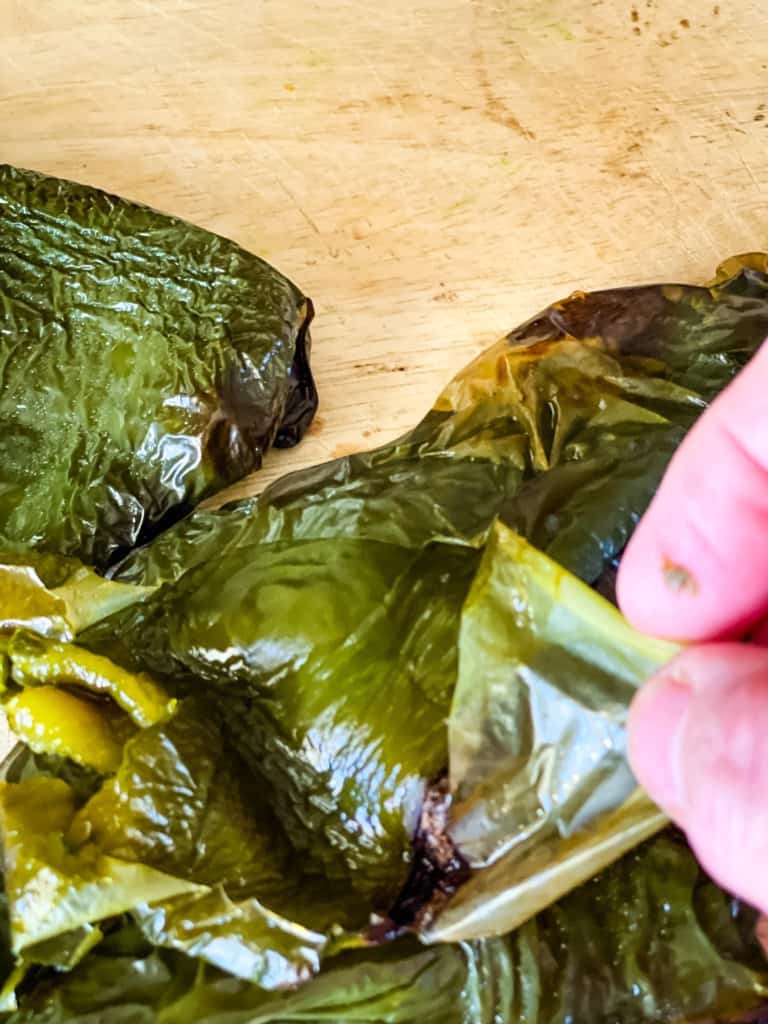 peeling the skin from a roasted poblano pepper