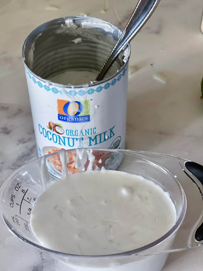 skimming the coconut cream from a can of full fat coconut milk