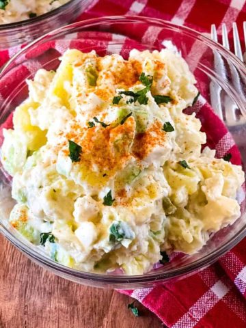 two glass bowls with potato salad on a red checked napkin