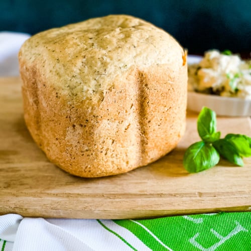 baked loaf of olive oil herb bread on a cutting board