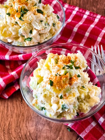 two glass bowls with potato salad on a red checked napkin