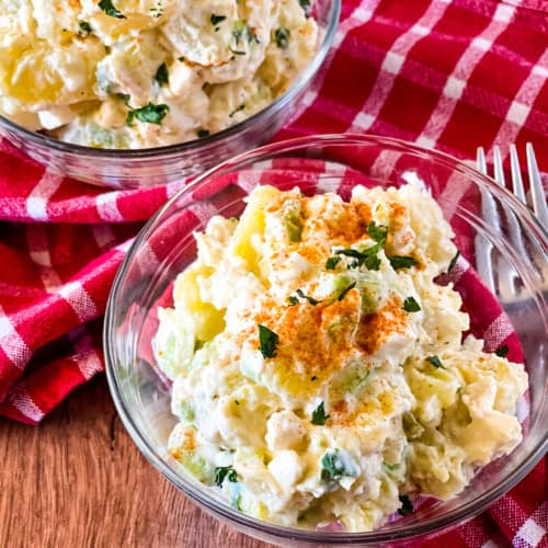 two glass bowls with potato salad on a red checked napkin