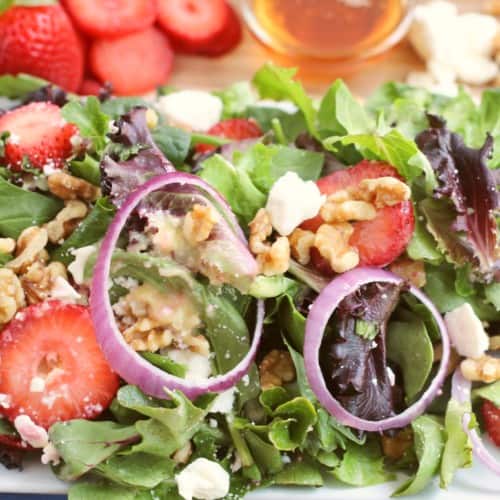 Strawberry walnut salad plated with strawberries, agave, vegan feta, and walnuts on the side
