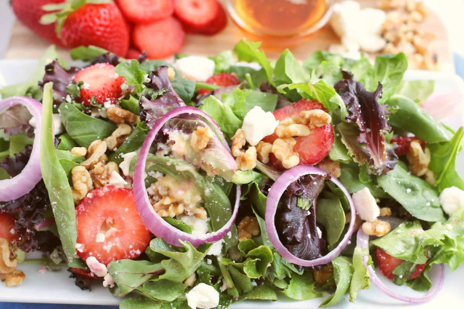 Strawberry walnut salad plated with strawberries, agave, vegan feta, and walnuts on the side
