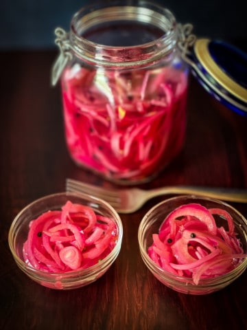 big jar and two small bowls with pink onions with fork l